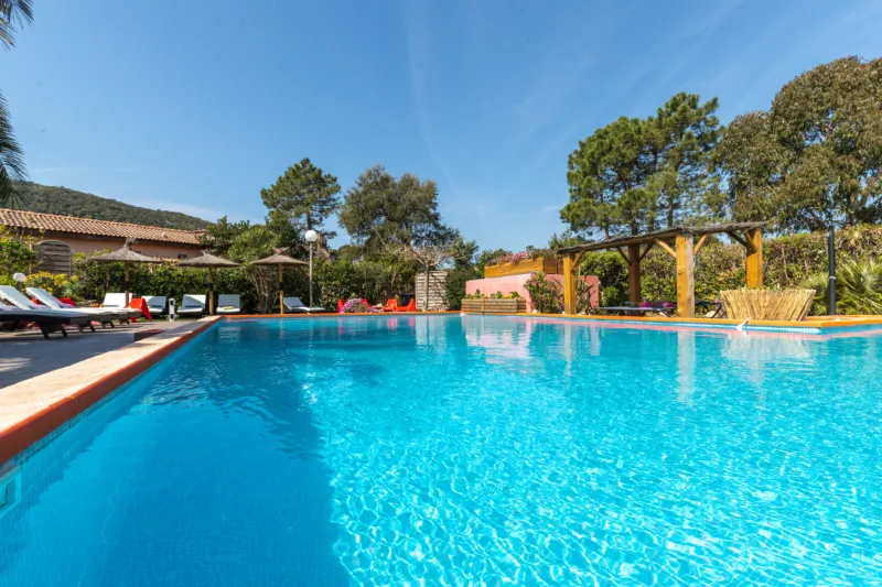 Grande piscine à débordement entourée de transats et parasols