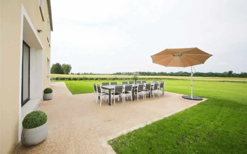Terrasse extérieure avec grande table et parasol pour les repas de groupe