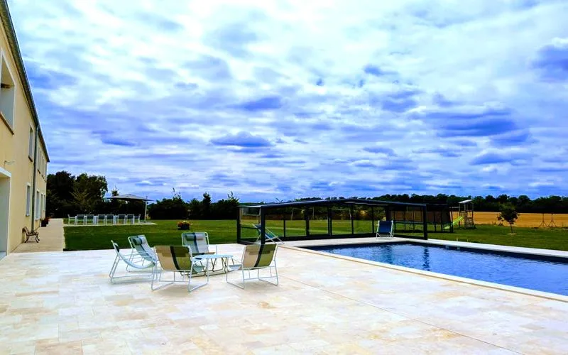 Terrasse en pierre avec mobilier de détente au bord de la piscine