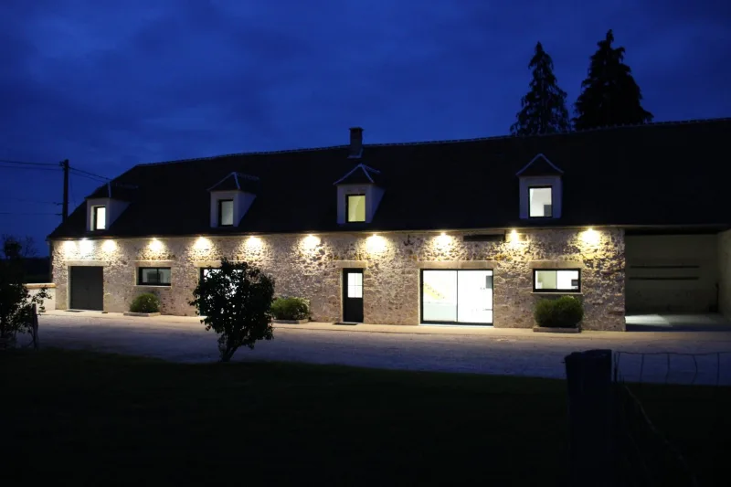 Façade en pierre du gîte illuminée à la tombée de la nuit