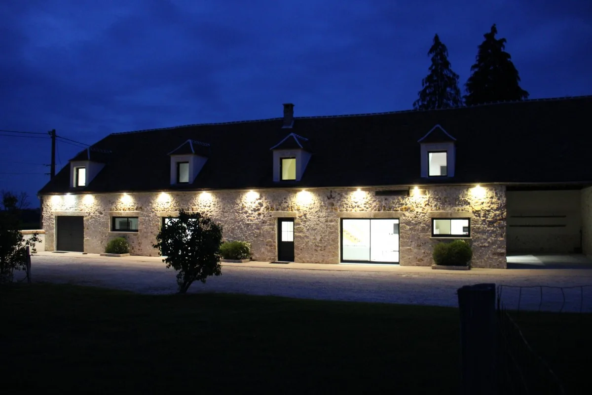 Gîte de groupe Entre Terres et Vignes à Châtillon-sur-Morin — Façade en pierre du gîte illuminée à la tombée de la nuit, capacité 12 personnes