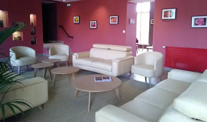 Grand salon commun aux murs rouges avec plusieurs canapés et fauteuils en cuir clair