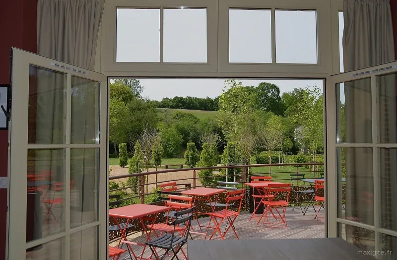 Terrasse en bois avec mobilier coloré et vue dégagée sur la vallée et le coteau boisé