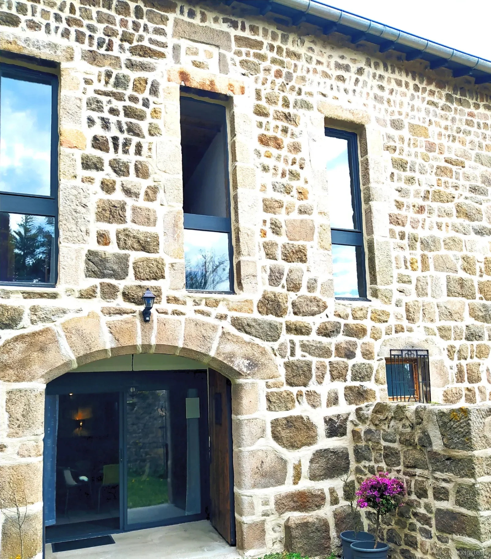 Gîte de groupe La Bâtisse aux Lanternes à Saint-Bonnet-le-Château — Façade en pierre de la Bâtisse aux Lanternes, entrée voûtée et fenêtres en pierre de taille, capacité 30 personnes
