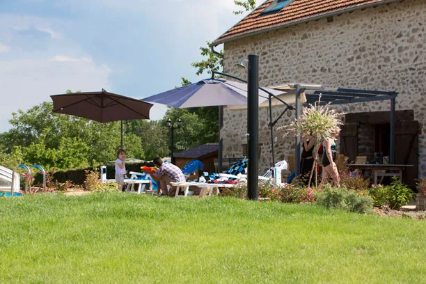 Piscine extérieure et vue sur la maison en pierre, gîte de la Jéraphie