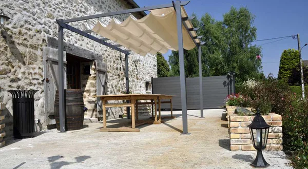 Gîte de groupe Gîte de la Jéraphie à La Souterraine — Terrasse couverte avec pergola et table en bois, gîte de la Jéraphie, capacité 15 personnes