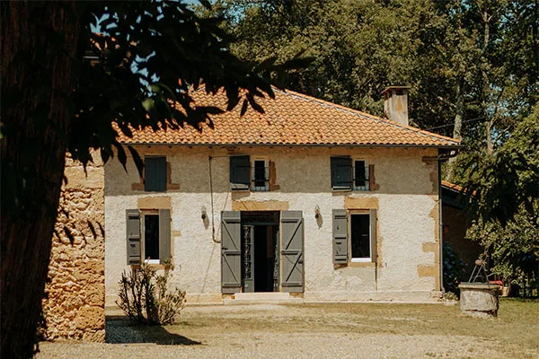 Façade principale en pierre du Domaine de Cap'Bat avec ses volets et son perron