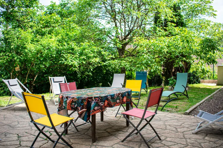 Jardin ombragé avec transats colorés autour d'une table sur la terrasse