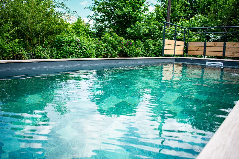 Piscine extérieure entourée de verdure avec plage en bois