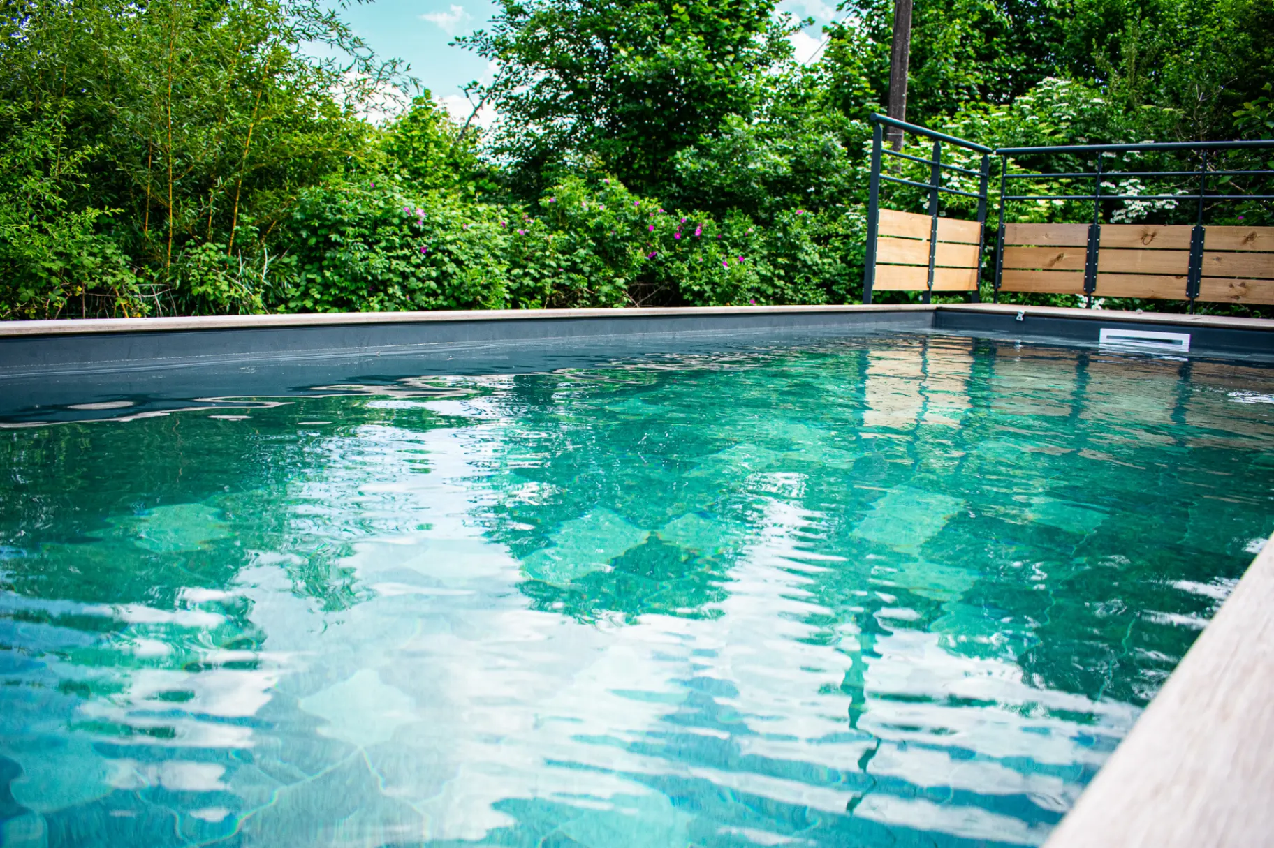 Gîte de groupe Le Gîte des Ronchots à La Rosière — Piscine extérieure entourée de verdure avec plage en bois, capacité 15 personnes