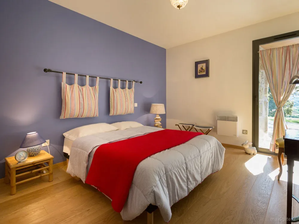 Chambre au mur bleu avec plaid rouge sur le lit