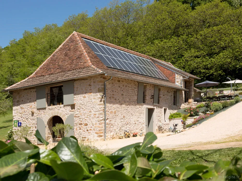 Gîte de groupe Gîte de la Papetie à Brivezac — Façade en pierre de l'ancienne grange rénovée, avec panneaux solaires en toiture, capacité 15 personnes