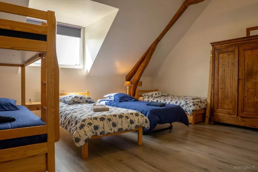 Chambre mansardée avec deux lits jumeaux fleuris sous poutres apparentes