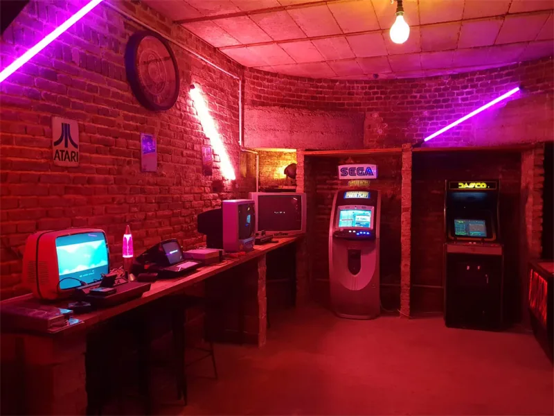 Coin jeux d'arcade avec néons roses, bornes lumineuses et mur en briques apparentes