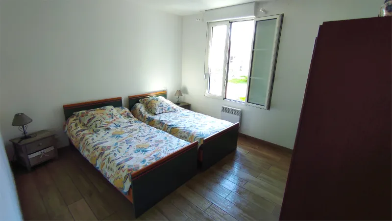 Chambre avec deux lits jumeaux, parquet et grande fenêtre donnant sur le jardin