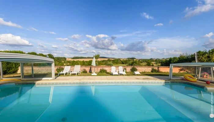 Piscine extérieure du domaine avec terrasse ensoleillée et vue sur la nature