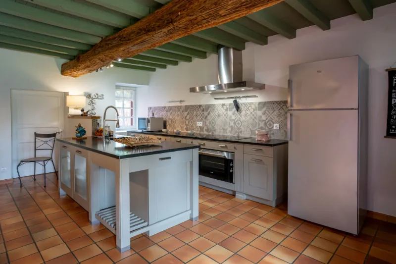 Cuisine américaine avec îlot central, plan de travail noir et carrelage à motifs