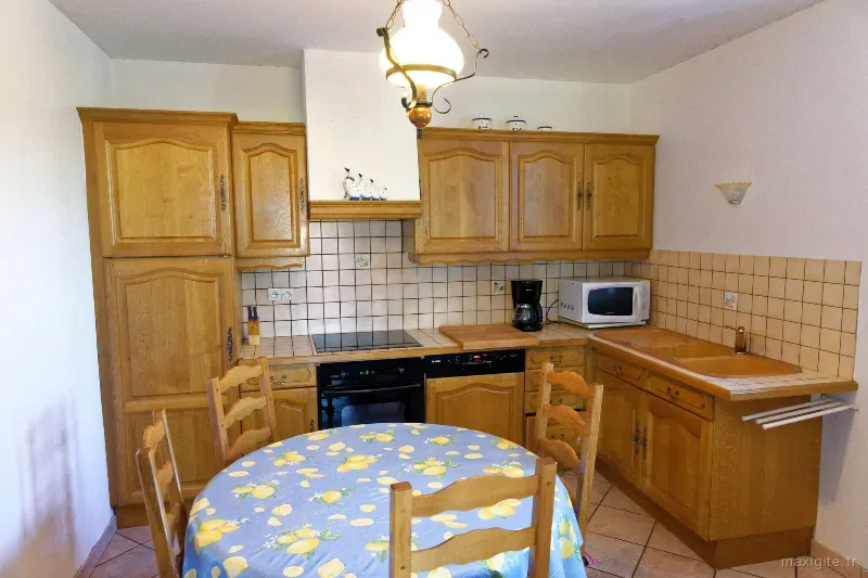 Cuisine équipée en bois avec table ronde et nappe à motifs de citrons