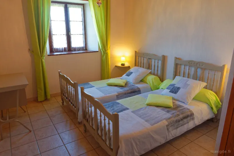 Chambre avec deux lits jumeaux et rideaux vert anis, ambiance lumineuse