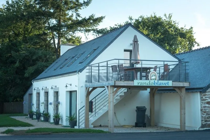 Façade du gîte de ferme rénové avec terrasse en bois surélevée et escalier extérieur