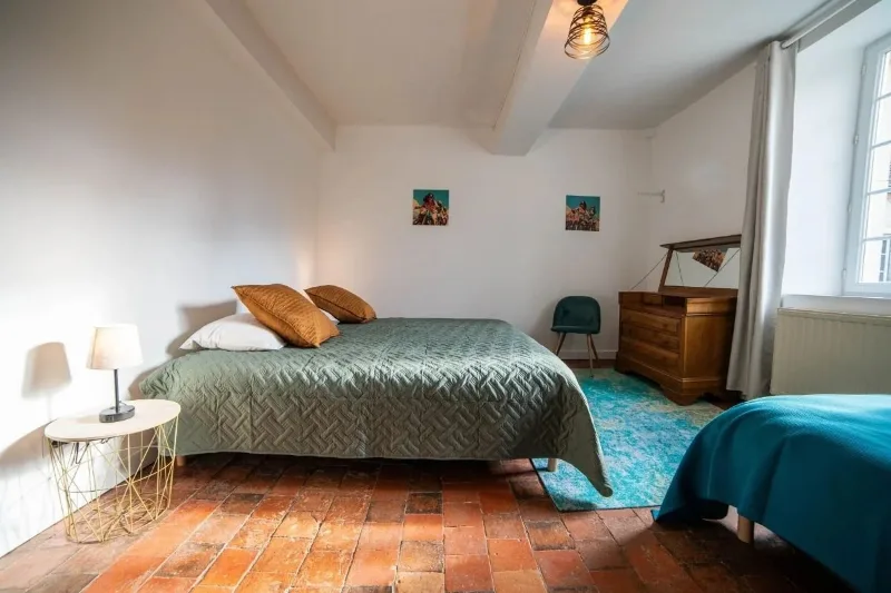 Chambre au sol en tomettes avec literie vert et moutarde et mobilier ancien