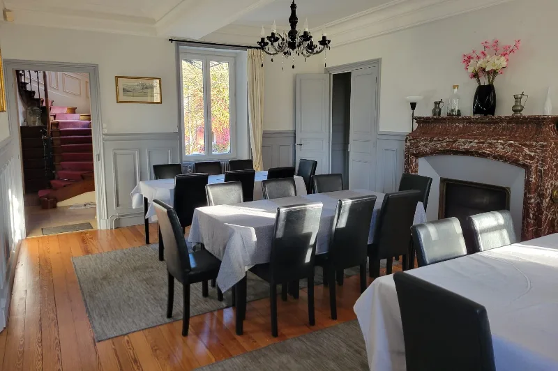 Grande salle à manger avec cheminée en marbre et tables dressées pour un grand groupe
