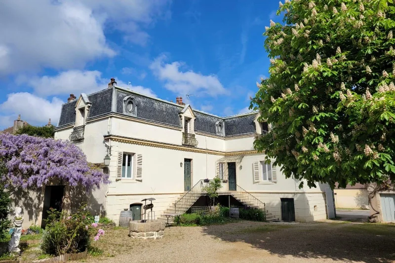 Façade en pierre calcaire de la maison de maître du 18e siècle avec glycine en fleurs