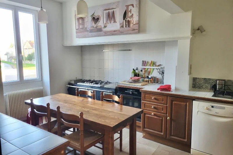 Cuisine équipée avec piano de cuisson, lave-vaisselle et grande table en bois