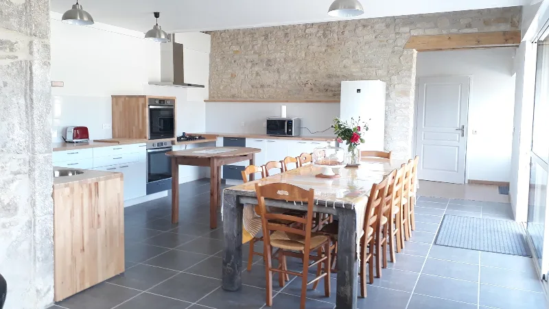 Cuisine ouverte entièrement équipée avec longue table en bois pouvant accueillir toute la tablée