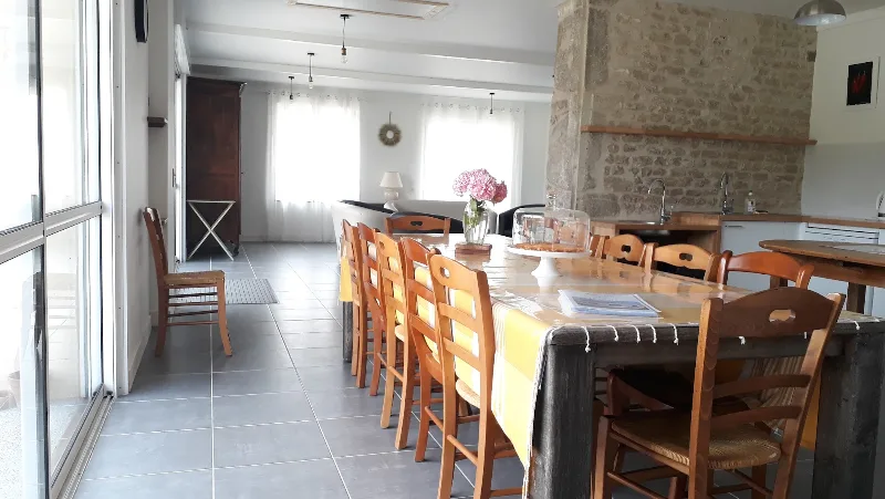 Coin repas convivial avec table en bois fleurie, ouvert sur le salon et les grandes baies vitrées