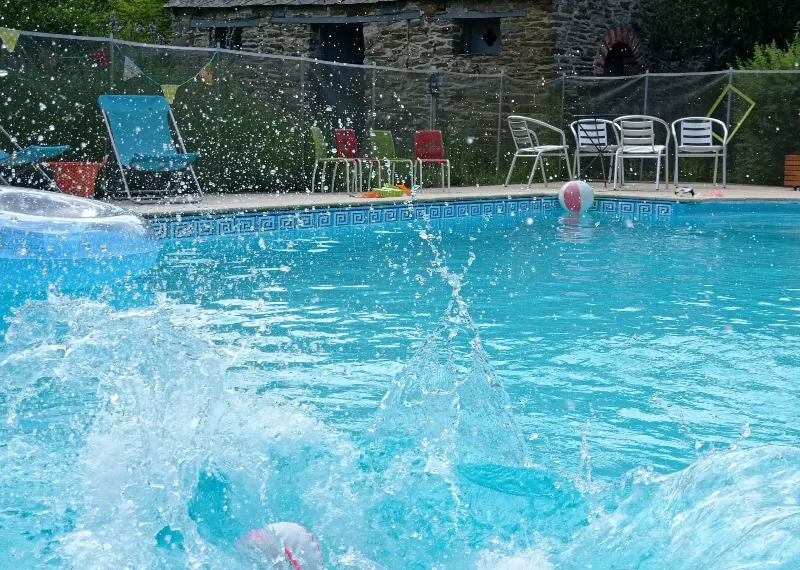 Piscine extérieure chauffée avec transats colorés et bâtiment en pierre en arrière-plan