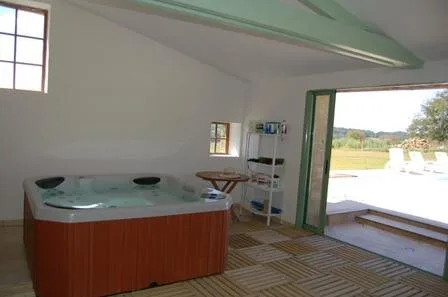Jacuzzi intérieur avec ouverture directe sur la terrasse et vue sur la piscine extérieure
