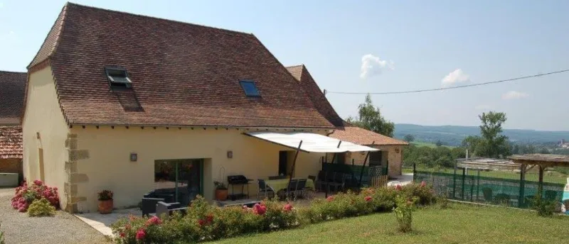 Façade du gîte Les Figuiers avec terrasse ombragée, mobilier de jardin et massifs de fleurs