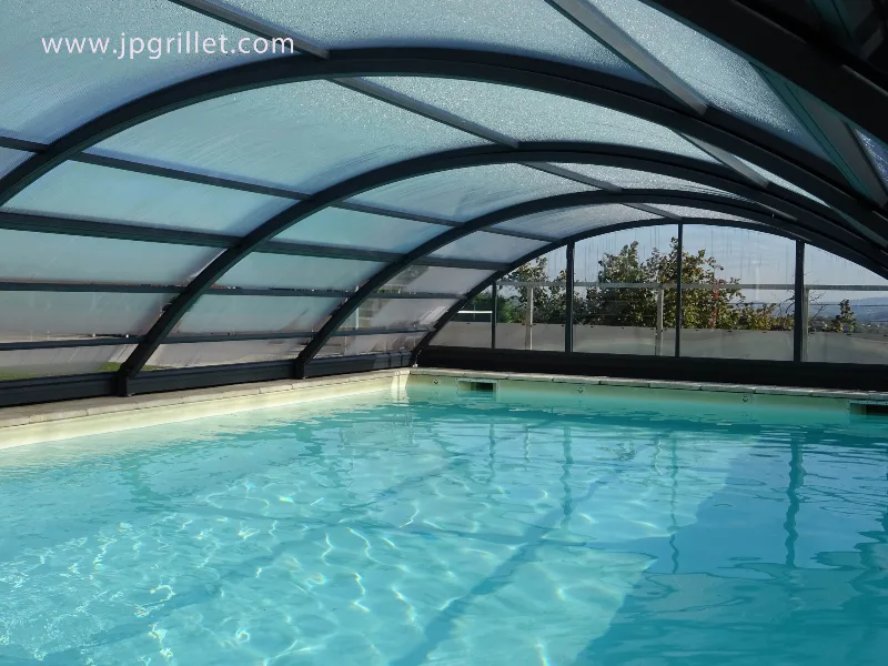 Piscine chauffée sous abri rétractable, avec vue sur les arbres et la terrasse extérieure
