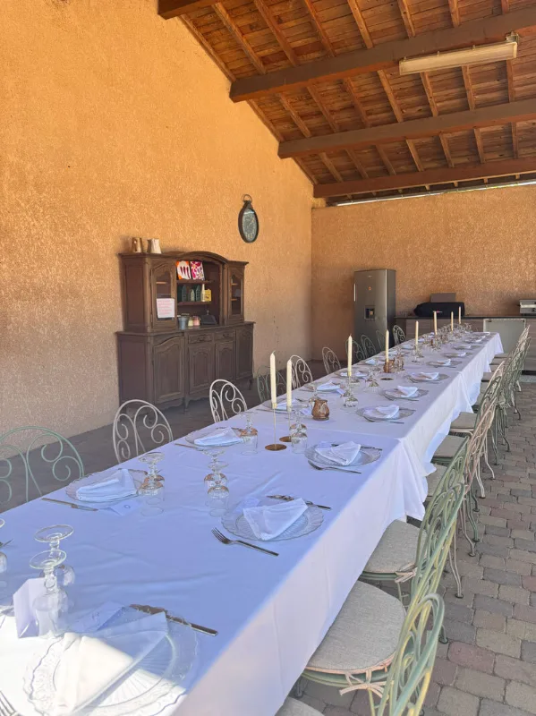 Longue tablée dressée sous préau couvert, pour un grand repas de groupe en extérieur