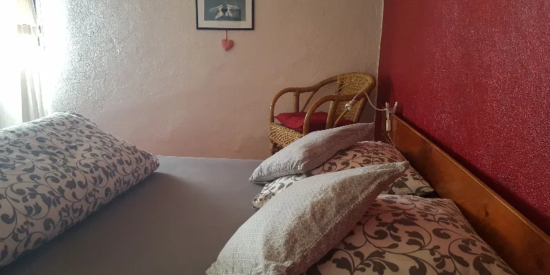 Chambre double lumineuse avec literie fleurie et fauteuil en rotin