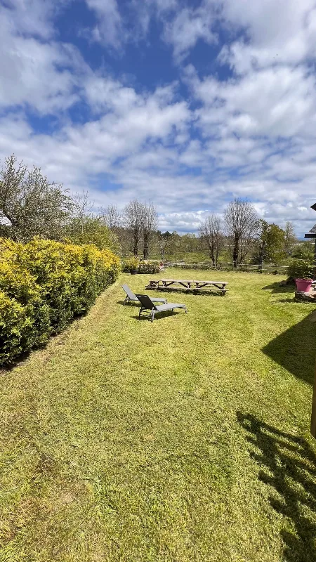 Jardin arboré avec transats et grande table de pique-nique face à la vue dégagée