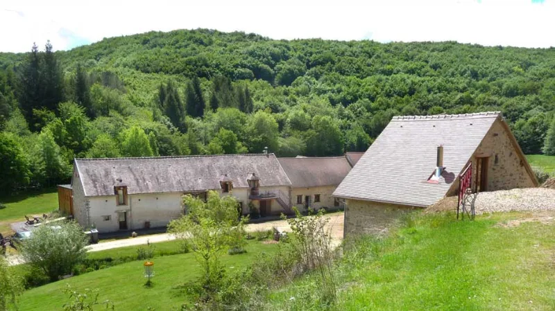 Vue extérieure du Moulin Berthon avec sa façade en pierre au cœur de la campagne auvergnate