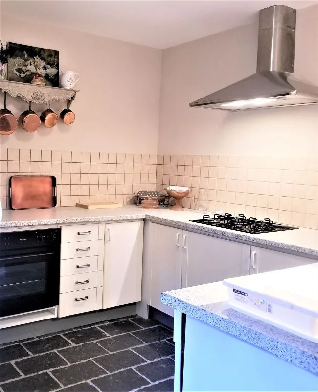 Cuisine équipée avec plaques de cuisson, hotte inox et casseroles en cuivre suspendues