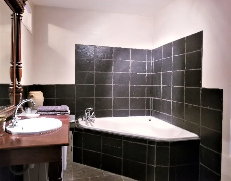 Salle de bain avec baignoire d'angle habillée d'ardoise et double vasque en bois