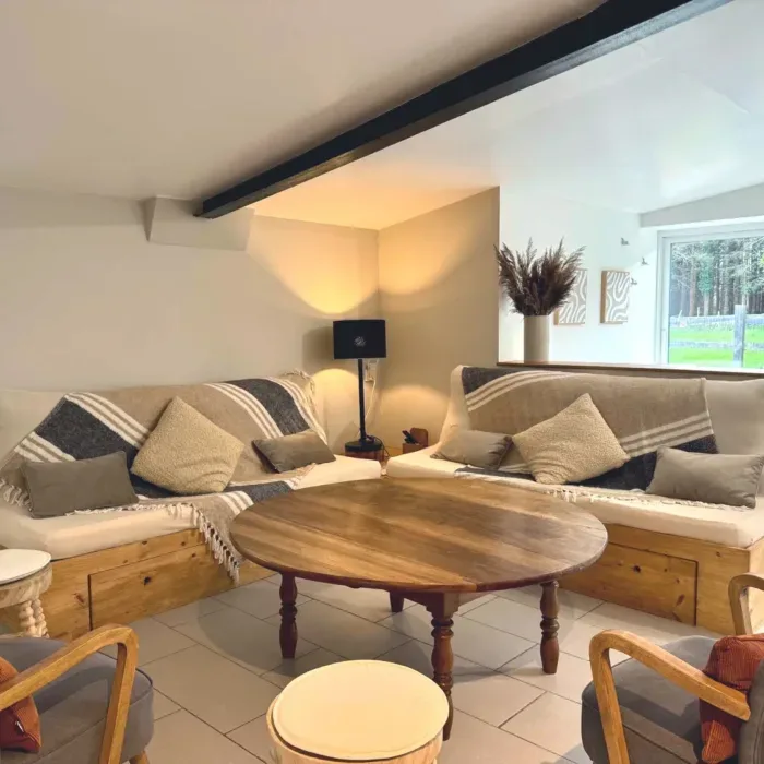 Salon cosy avec canapés en angle, coussins et table basse ronde en bois
