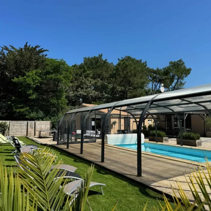 Piscine privée couverte et chauffée entourée d'une terrasse et d'un jardin clos