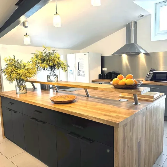 Cuisine américaine équipée avec grand îlot central en bois et hotte inox