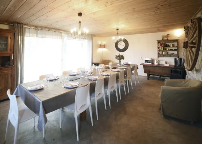 Grande salle à manger en bois avec longue tablée dressée pour quatorze convives