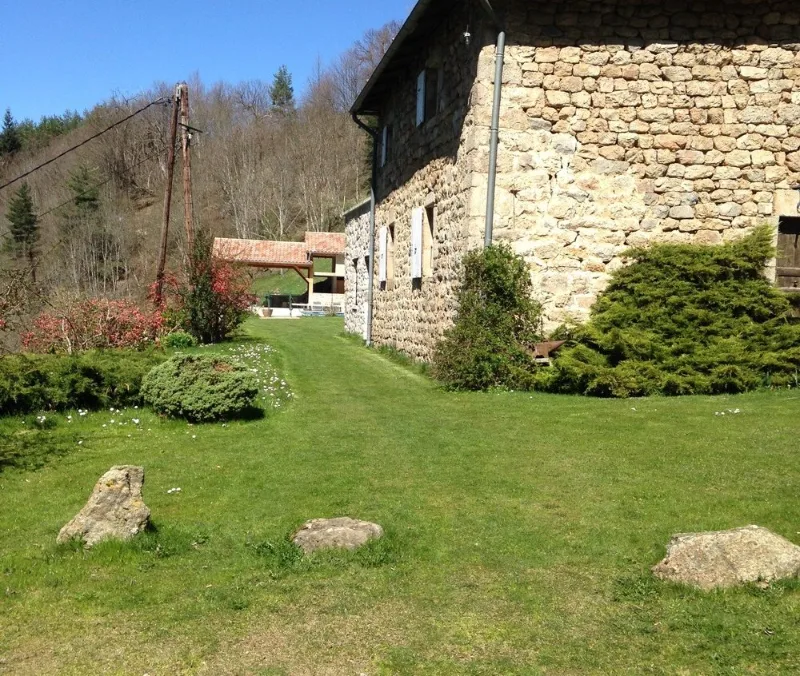Vue extérieure de la ferme en pierre ardéchoise au milieu d'un grand jardin arboré