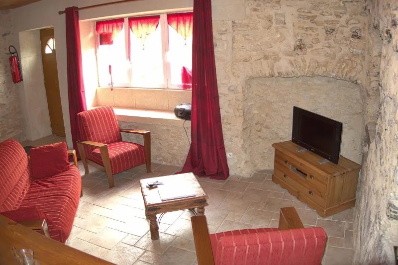 Salon avec cheminée en pierre, fauteuils et canapé pour se détendre