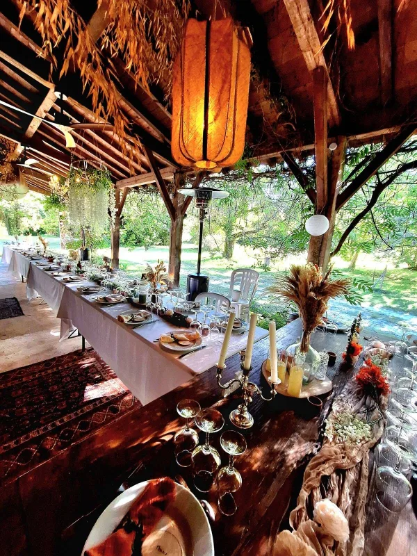 Grande table de repas dressée sous la grange, ambiance conviviale