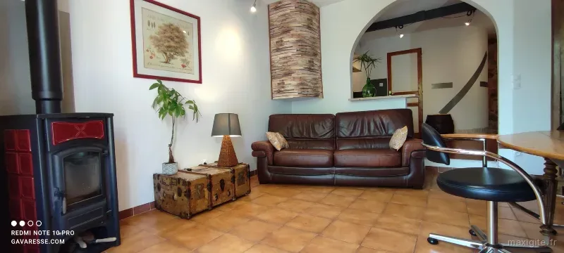 Salon cosy avec poêle à bois, canapé en cuir et décoration provençale