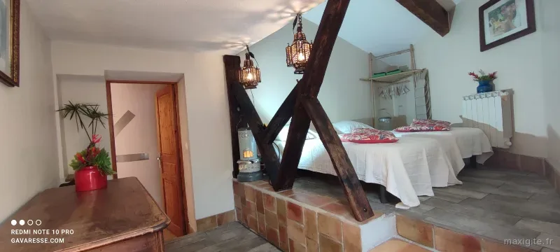 Chambre à l'ambiance chaleureuse avec poutres apparentes et lits doubles