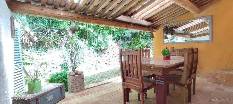 Terrasse couverte commune avec grande table et vue sur le jardin arboré